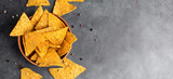 Corn Mexican tortilla chips snack on a black dark background. Food photo decorated with ketchup tomato sauce and salt.