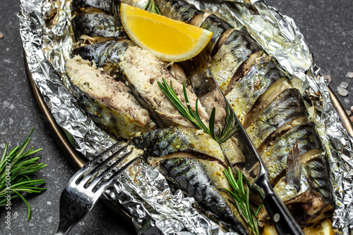 delicious roasted mackerel fish with lemon herbs and spices on a dark background, banner, Food recipe background. Close up, top view
