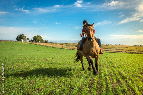 woman rides a horse and rides through the hills of a field