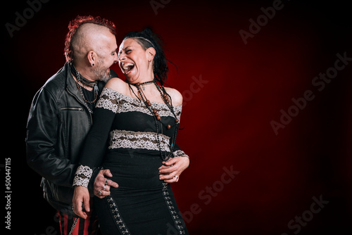 punk man and woman couple look at each other and laugh excitedly in studio shot
