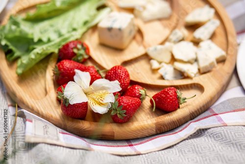 Strawberries on a cheese plate. Outdoor picnic.