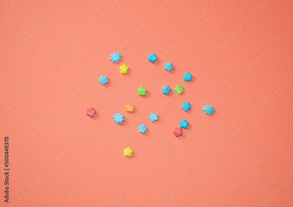 Powdered sugar in the form of stars for confectionery on an orange background top view. Powdered sugar in the form of stars for confectionery on an orange background top view.