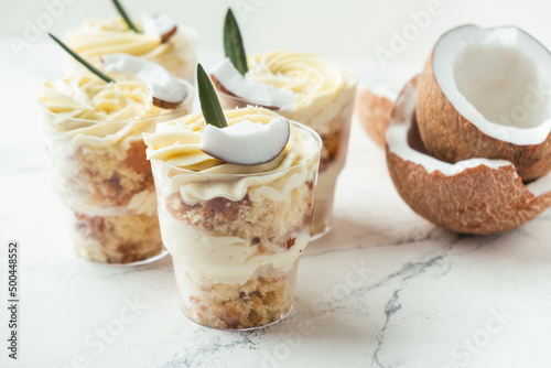 English layered dessert trifle of buscuit dough, custard and whipped cream with fresh coconut pieces on the white background photo