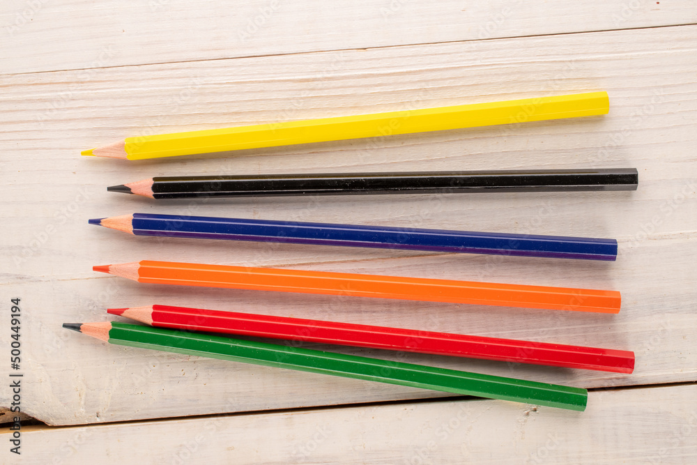 Several colored pencils on a wooden table, close-up, top view. Several colored pencils on a wooden table, close-up, top view.