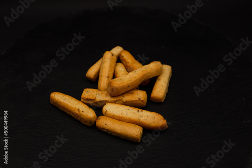 Grissini lying on a plate on a black background