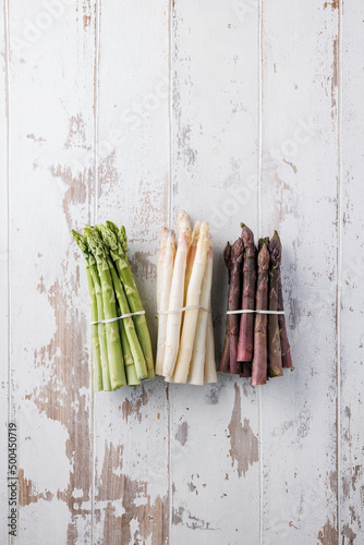 Green, white and purple asparagus on a kitchen background © karepa