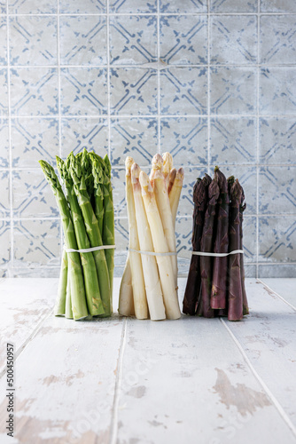 Green  white and purple asparagus on a kitchen background