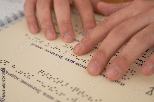 Visually impaired man reading a braille book. 