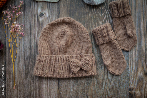 New handmade project, woolen mittens and hat, on dark wooden background