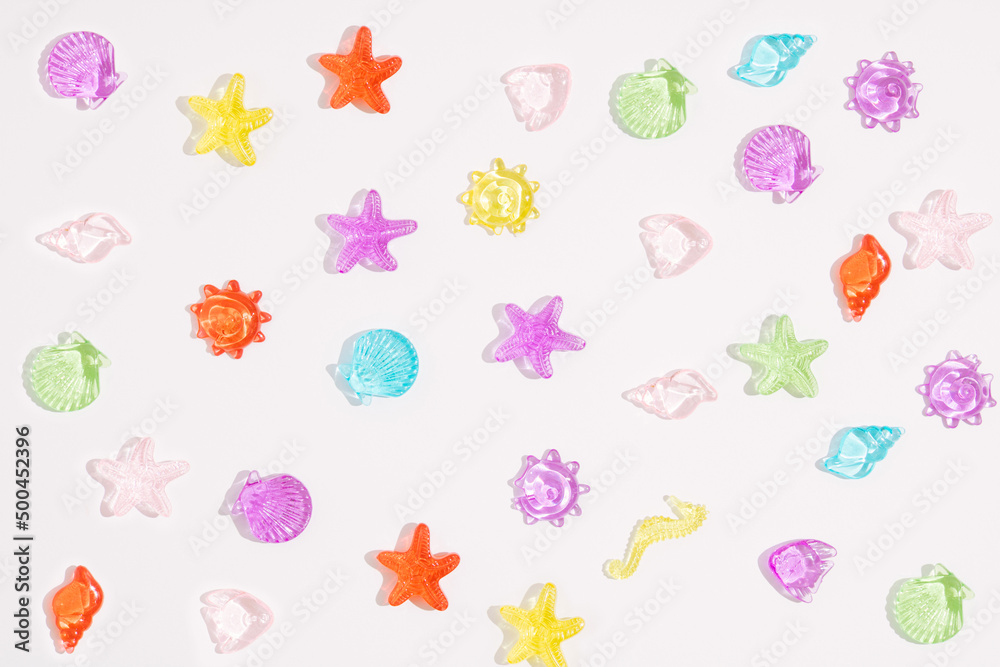 Creative composition made with colorful plastic shells and starfish on white background. Summer vacation pattern.