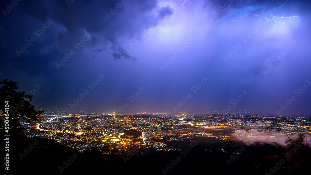 aerial view City night from the view point on top of mountain in raining storm clouds with lightning , Chiang mai ,Thailand