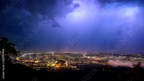 aerial view City night from the view point on top of mountain in raining storm clouds with lightning   Chiang mai  Thailand