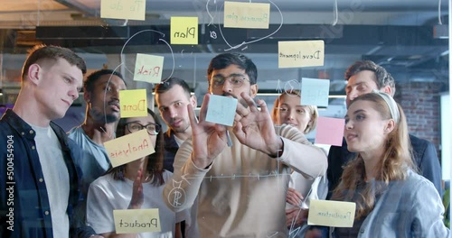 Multiethnic working team making plans for company future and sticking to-do notes. Diverse males and females emplyees brainstorming and planning work for startup project. Management strategy