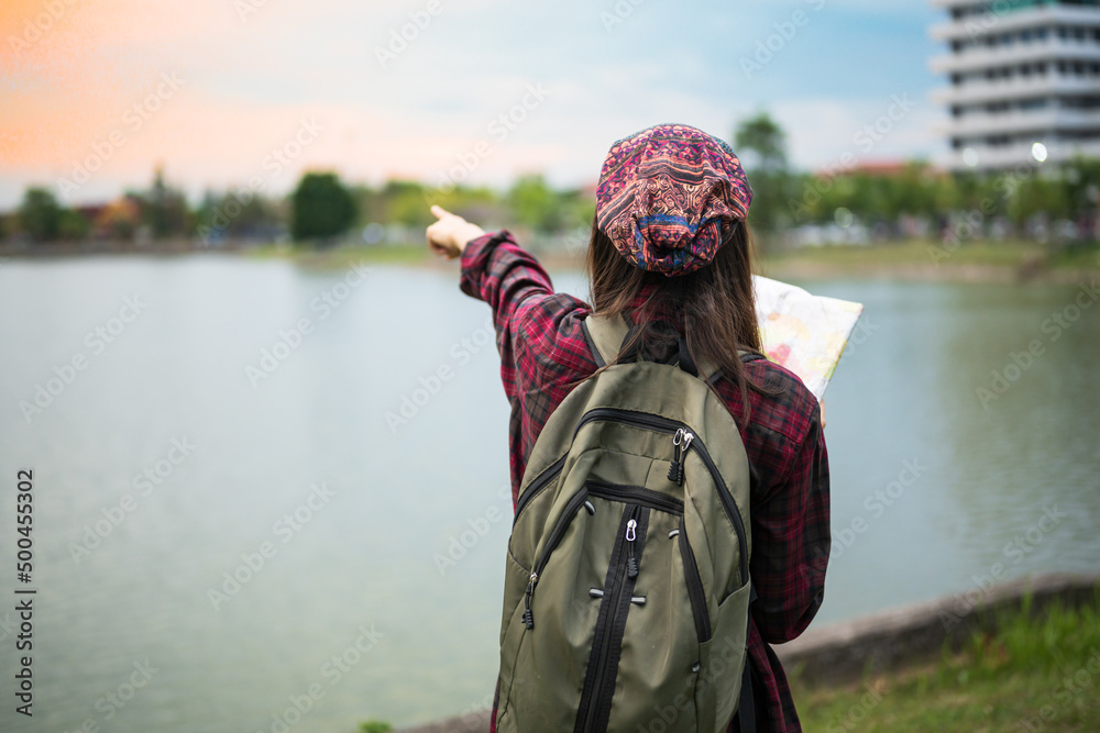 Asian hipster young girl backpack tourist hand holding a map for search and plan her trip.Woman traveler and green bag in the park during vacation.