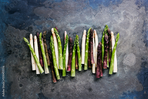 Green, white and purple asparagus on a kitchen background photo