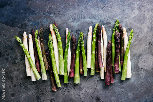 Green, white and purple asparagus on a kitchen background © karepa