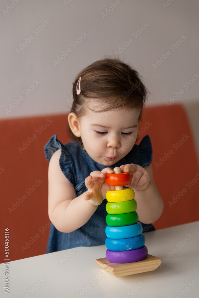 Baby girl playing with wooden colourful toy pyramid at home. Baby girl playing with wooden colourful toy pyramid at home.