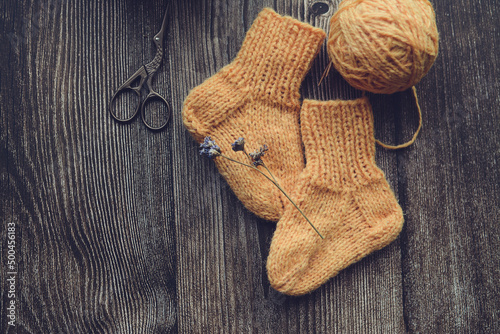 Packing small orange color baby socks, made of organic sheep wool