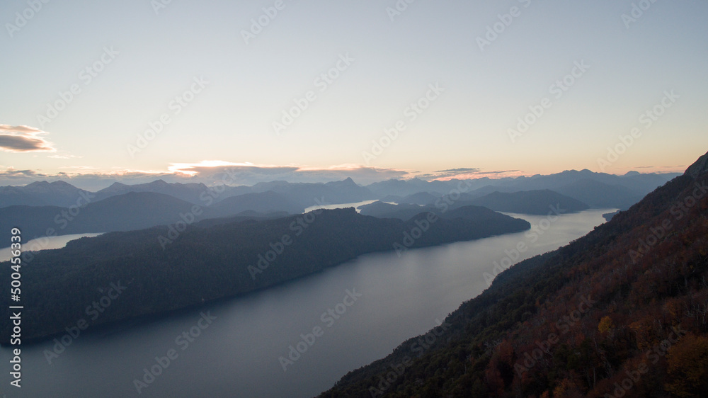 Magical landscape from the top of the hill. Panorama view of the forest, lake, valley and mountains at sunset. 