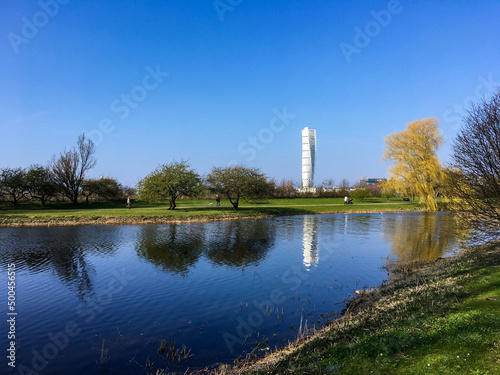 Bright spring day in park in Malmö Sweden with reflections of skyscraper in pond water