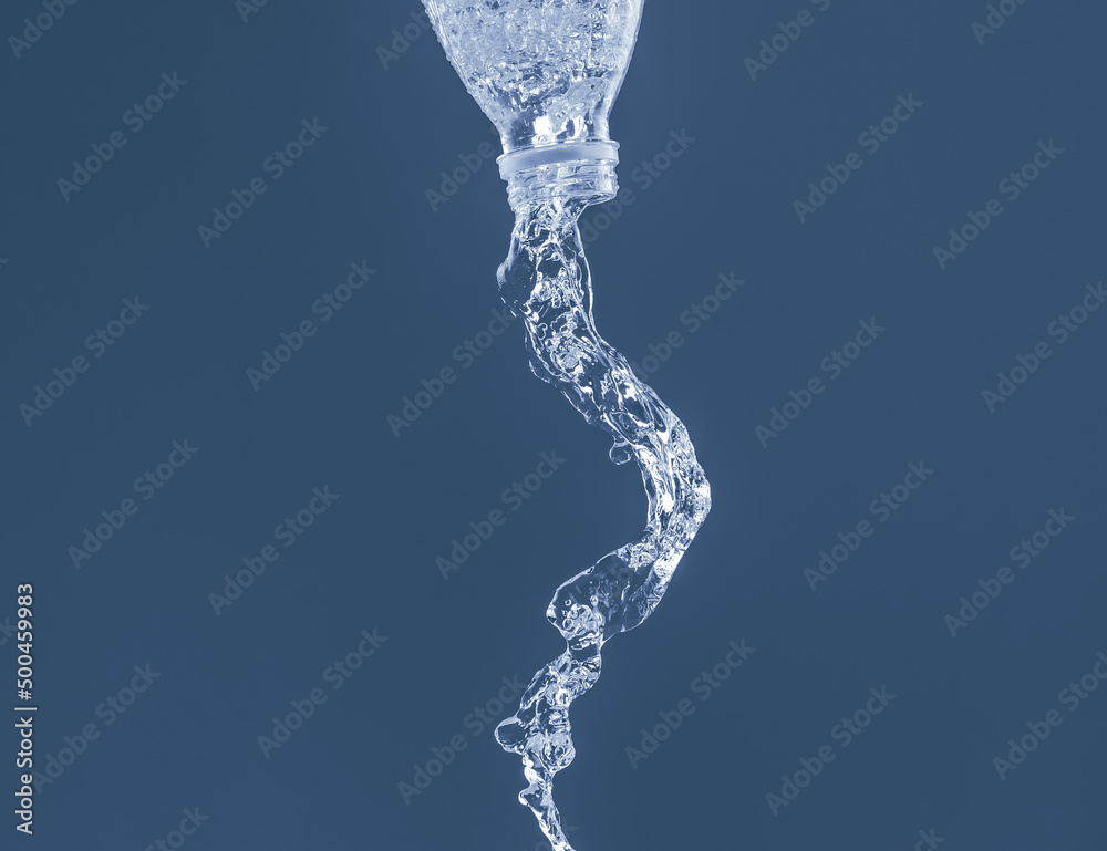 Splash of water from a bottle on a blue background. Reflection on the surface of the water. Splash of water from a bottle on a blue background. Reflection on the surface of the water.
