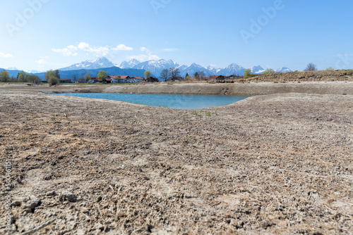 environmental protection, drought in germany and europe, a dried up lake in the alps, in the background mountains and houses