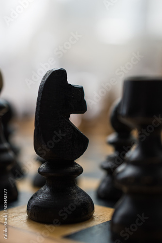 Chess board with figures. The figure of a horse in focus.