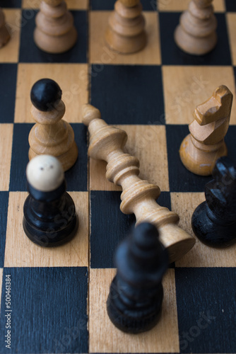 Chess board with figures. The concept of victory, the king is dead on the battlefield.