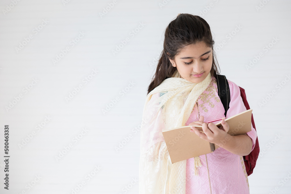 cute Indian girl smiling and writing on notebook for learning, education concept cute Indian girl smiling and writing on notebook for learning, education concept