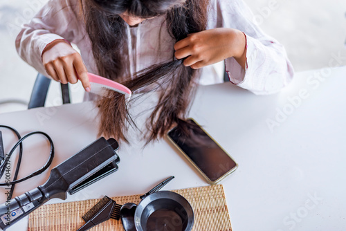 Damaged Hair, frustrated asian young woman, girl hand in holding brush splitting ends messy while combing hair, unbrushed dry long hair. Health care beauty concept.