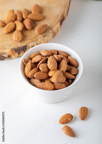 Almonds in white bowl on white background.