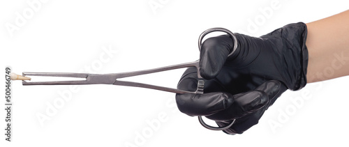 A doctor's hand in a black medical glove holds a child's molar tooth in a clamp. Studio photo