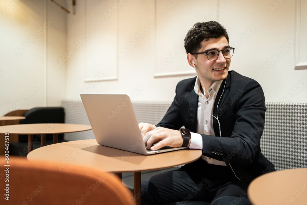 Manager with glasses in a business suit working office, using a laptop answering a client's email Manager with glasses in a business suit working office, using a laptop answering a client's email