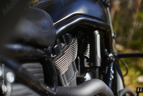 black motorcycle engine block with cooling radiators, pipes and gas tank