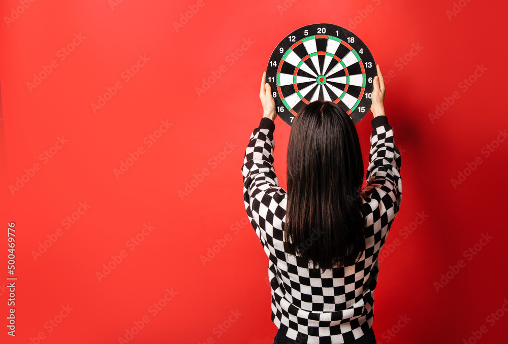 Woman stands with her back to us and holds the target over her head. Background with copy space.