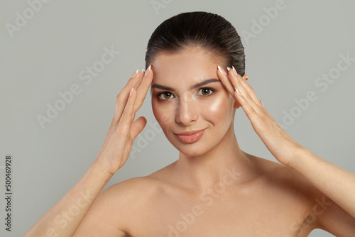 Young female model touching her face on grey background, portrait