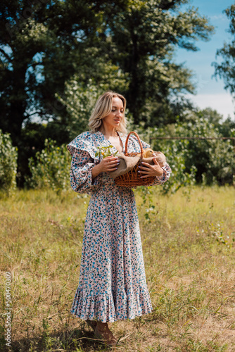 A young beautiful girl holds a basket with ducklings in her hands