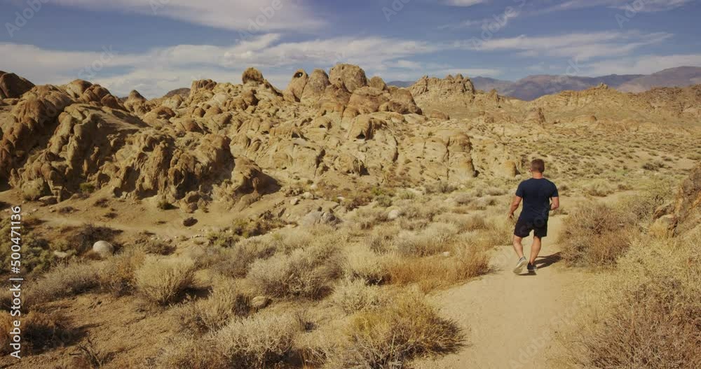 Man takes photo then walks on dirt trail in Alabama Hills, California Man takes photo then walks on dirt trail in Alabama Hills, California