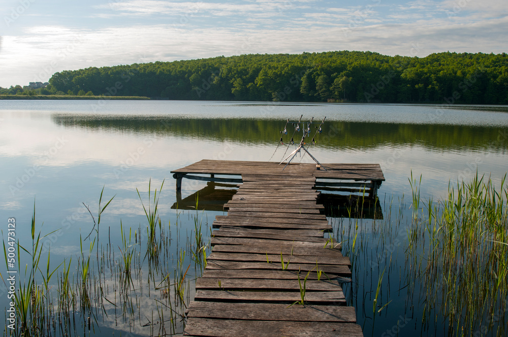 Fototapeta premium fisherman with fishing rods at sunrise on the lake