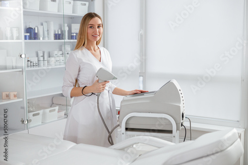 Young woman standing near laser epilation machine in beauty salon