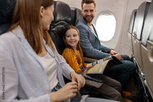 Cheerful little girl traveling with parents on airplane
