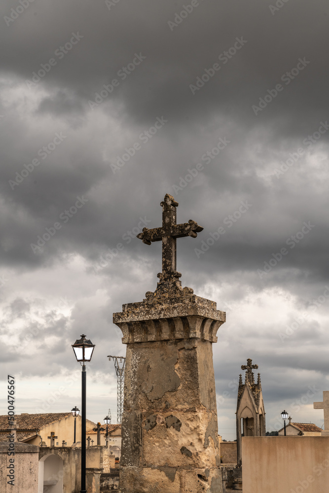 Großer Grabstein mit einem Kreuz vor dunklen Wolken
Friedhof auf Spaniens Insel Palma de Mallorca