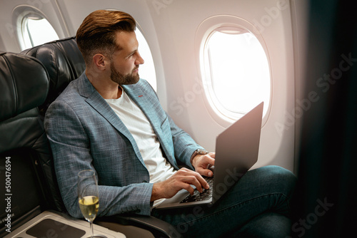Tela Male passenger working on laptop in airplane