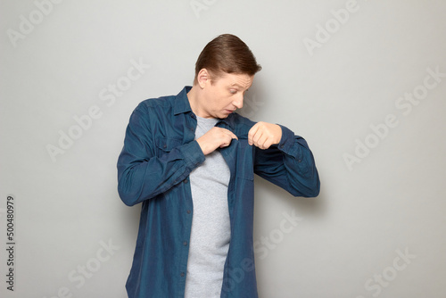 Portrait of surprised man looking with curiosity inside chest pocket