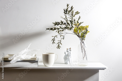 A vase with the dry branch of eucalyptus, wrinkled paper, a figurine of fox. Scandinavian style.