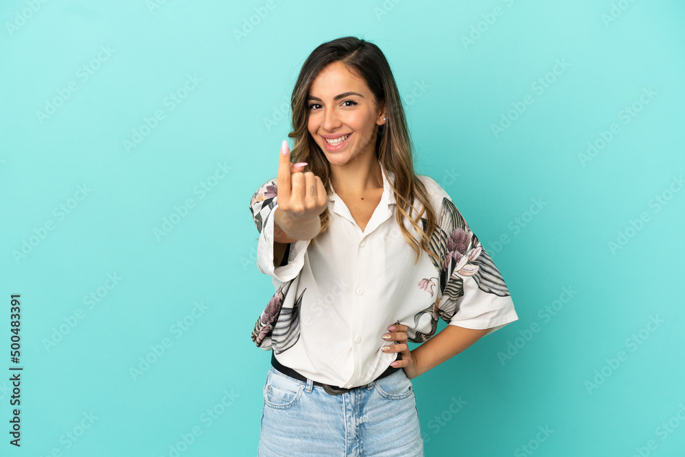 Young woman over isolated blue background doing coming gesture Young woman over isolated blue background doing coming gesture