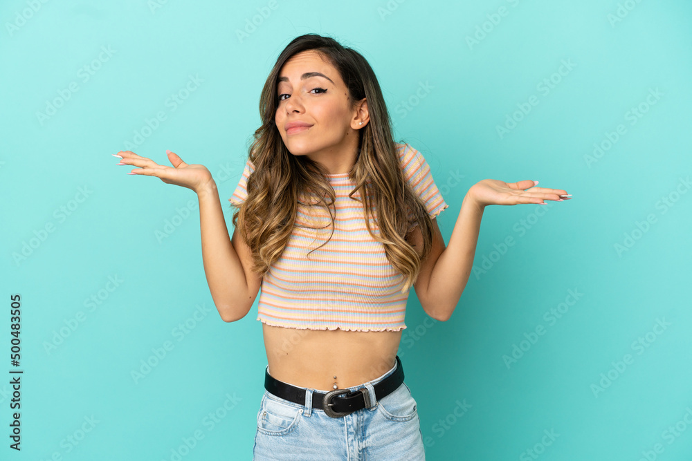 Young woman over isolated blue background making doubts gesture Young woman over isolated blue background making doubts gesture