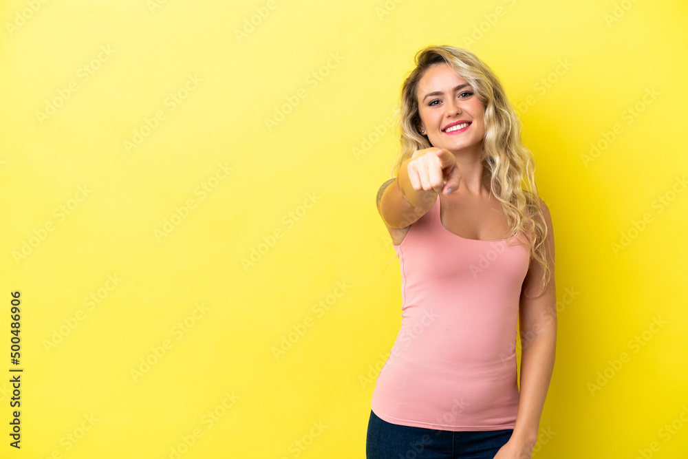 Young Brazilian woman isolated on yellow background pointing front with happy expression Young Brazilian woman isolated on yellow background pointing front with happy expression