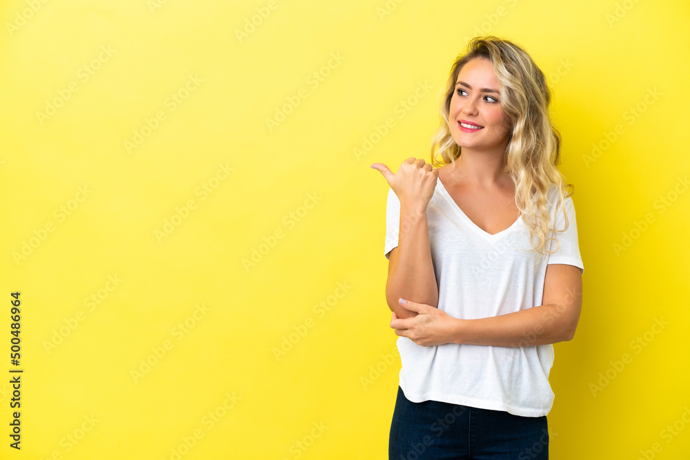 Young Brazilian woman isolated on yellow background pointing to the side to present a product Young Brazilian woman isolated on yellow background pointing to the side to present a product