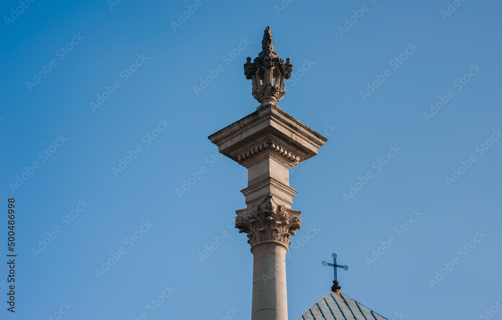 Ancient medieval column of the Bernardine church in Lvov, Ukraine. Blue sky and a cross on the roof.